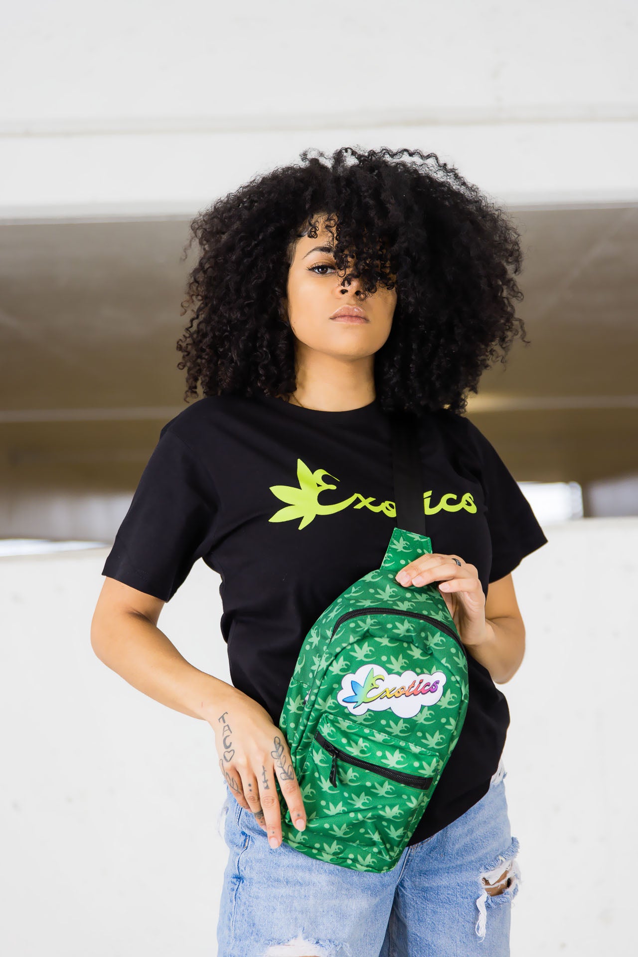 Woman holding green Exotics crossbody shoulder bag with rainbow logo