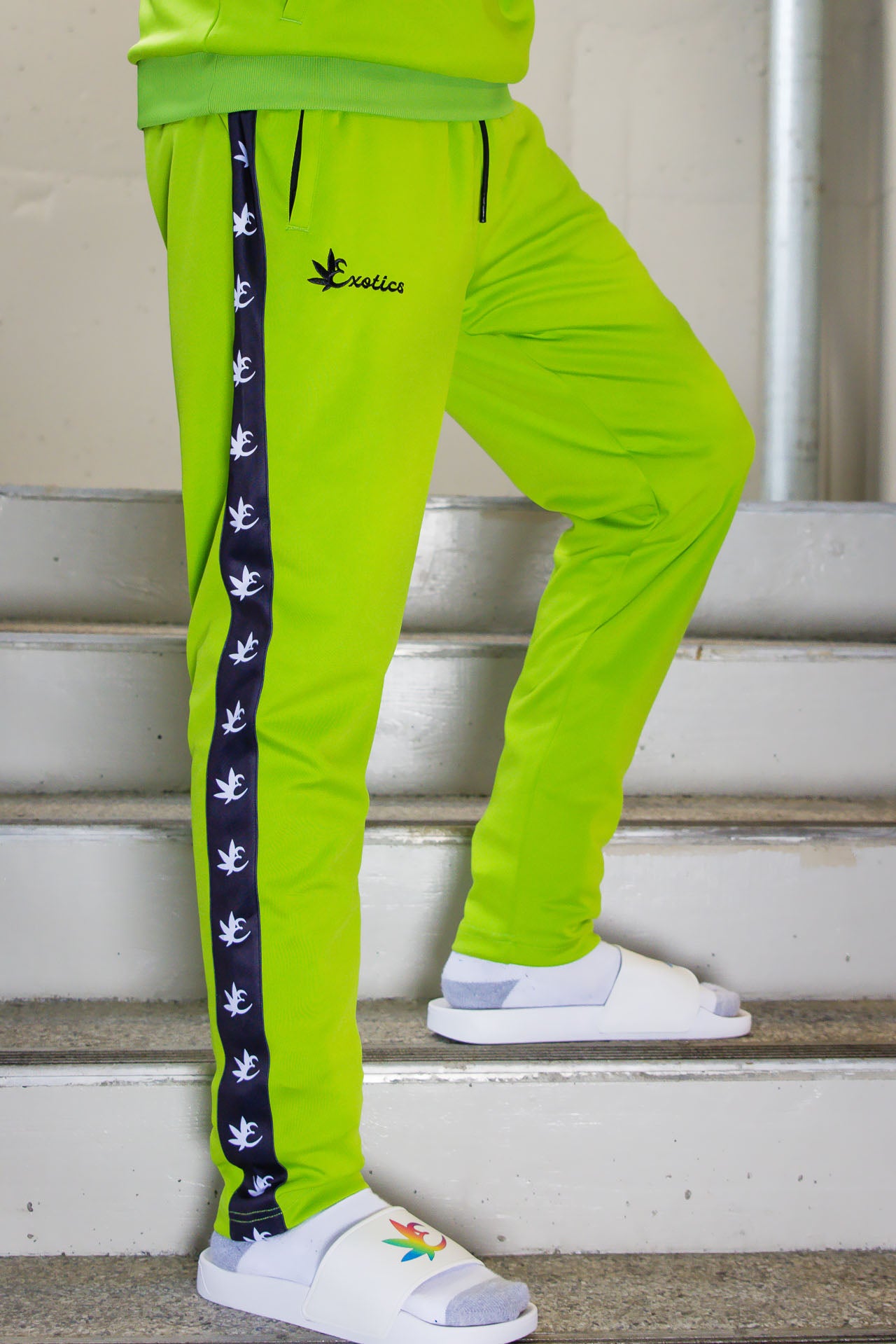 Green Exotics tracksuit and white slides in stairwell