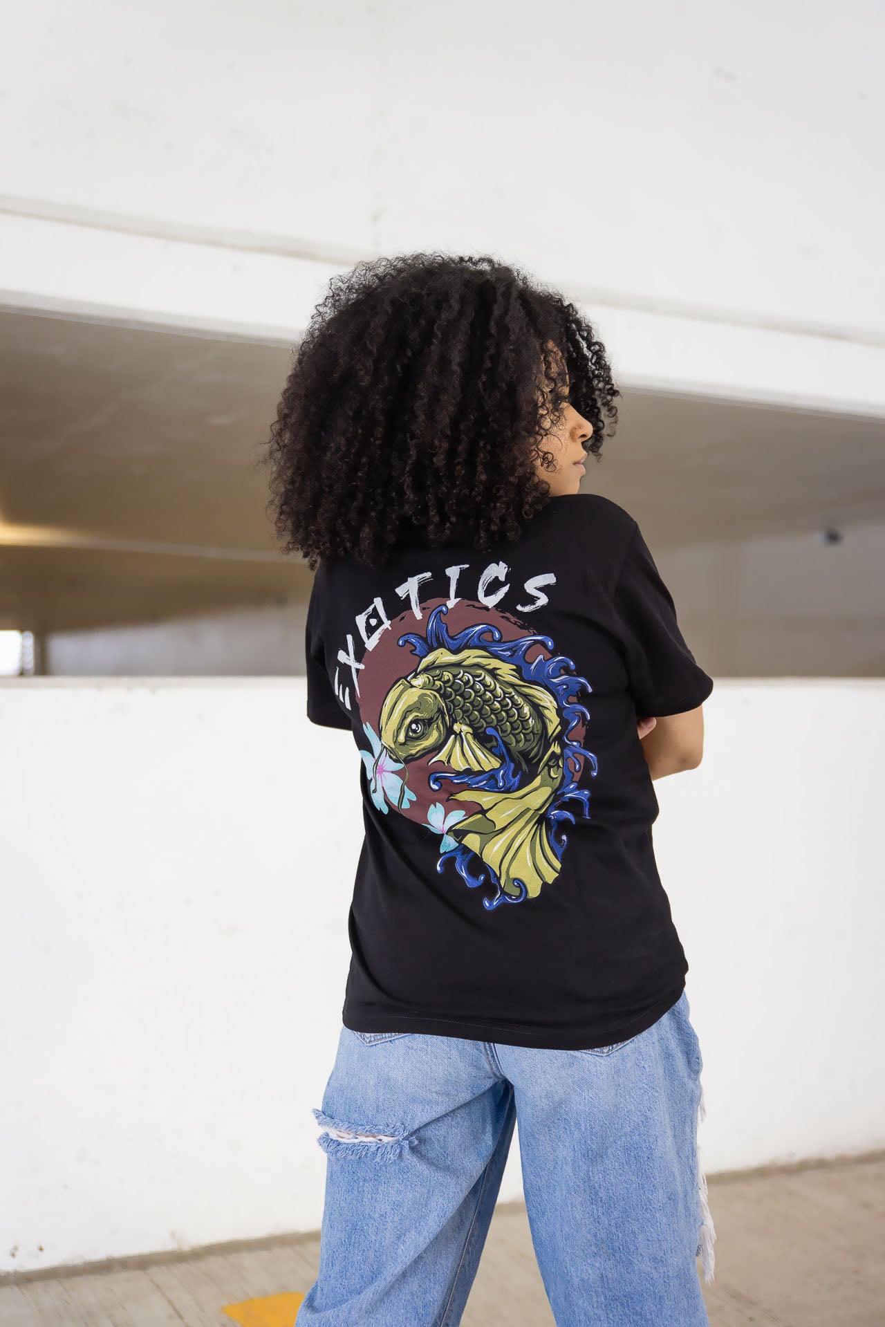 Back of woman wearing black Exotics tee t-shirt with koi fish design