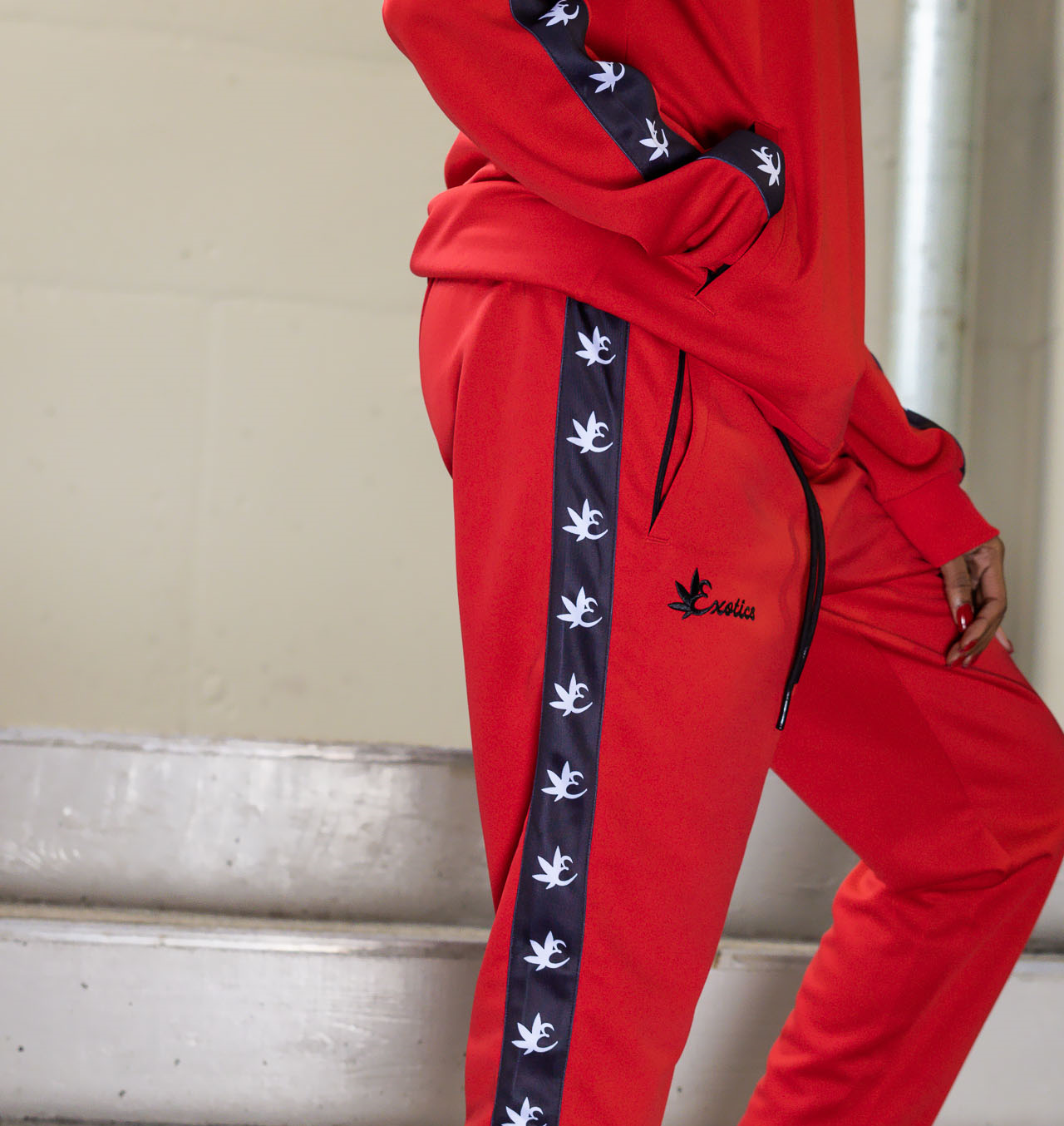 Woman wearing red Exotics tracksuit with black logo and details